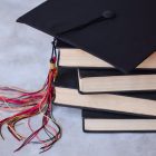graduation-cap-with-a-stack-of-books-on-gray-backg-2023-11-27-04-55-02-utc