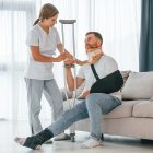 Nurse is helping injured man at home.